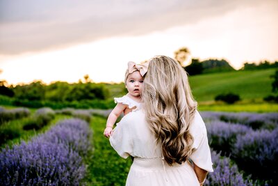 mom holding her daughter in a purple lavender field at whitehall maryland