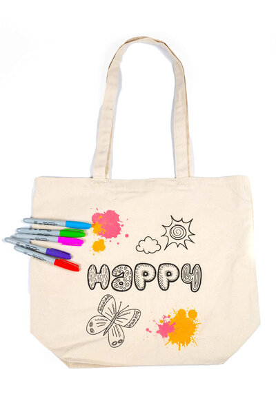 Commercial product shot of a canvas tote bag, with markers next to it, to show that the Luua canvas tote can be customized to each child's liking.