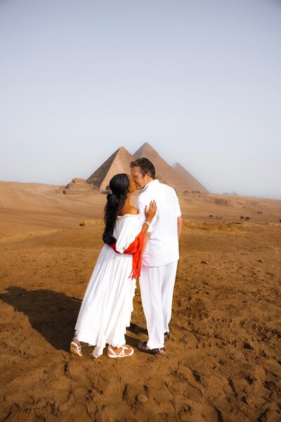 Couple embraces for a kiss in front of pyramids