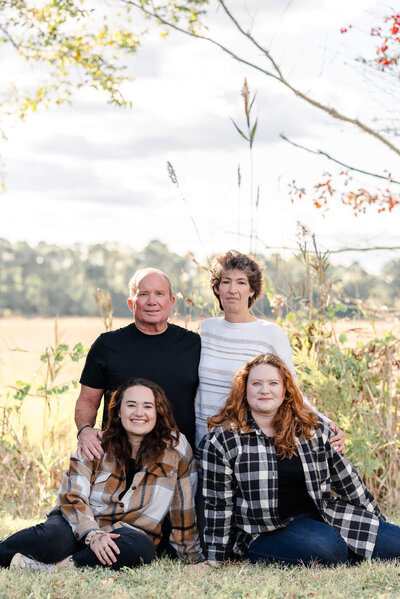 A family consisting of two parents and their adult daughters smile for the camera at Bells Mill Park in Chesapeake, Virginia.