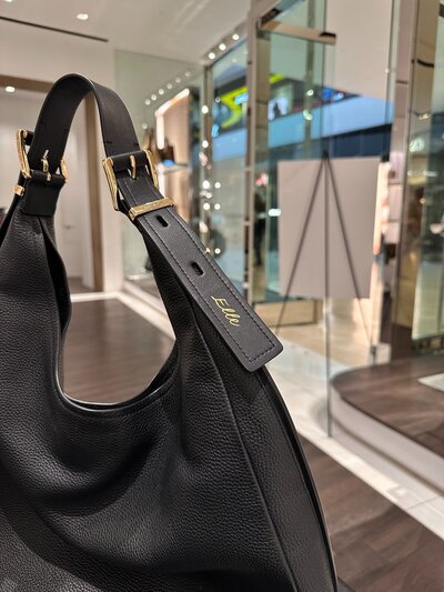 Name hand-painted on black leather handbag.