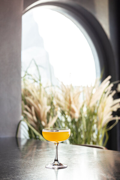 A cocktail sits upon a bartop.