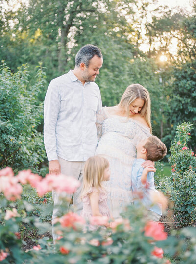 Mother and father stand in the Bon Air Rose Garden, looking down at their young son and daughter during their Maryland Family Photo Session