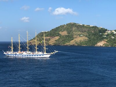 Classic white sailing yacht cruising past lush green islands in the Caribbean.
