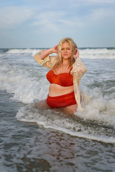 Plus size model posed flatteringly in the ocean, while waves crash over her at sunset in Myrtle Beach, SC.
