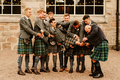 Groom is lifted sideways by groomsmen at fun alternative scottish wedding