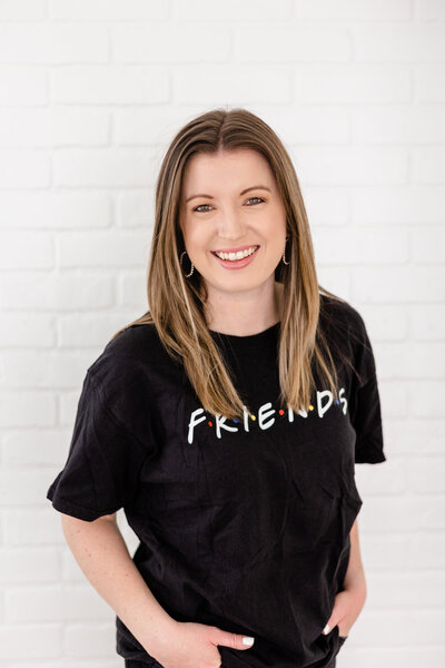 Girl smiling in front of white wall with Friends tv show shirt on