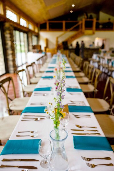 A long rectangular wedding reception table with chairs on either side.