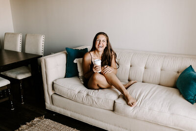 Morgan, a wedding and elopement photographer and photography educator, sitting on the couch with a coffee and smiling at the camera, offering educational resources, workshops, and coaching for photographers on the Education for Photographers page.