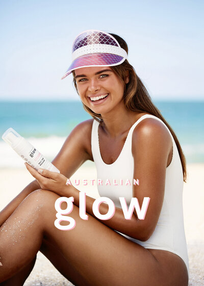 Beautiful woman on beach holding Australian Glow tanning product.