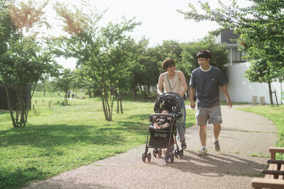 柔らかな光の中パパとママと赤ちゃんがベビーカーで公園をお散歩しているシーン