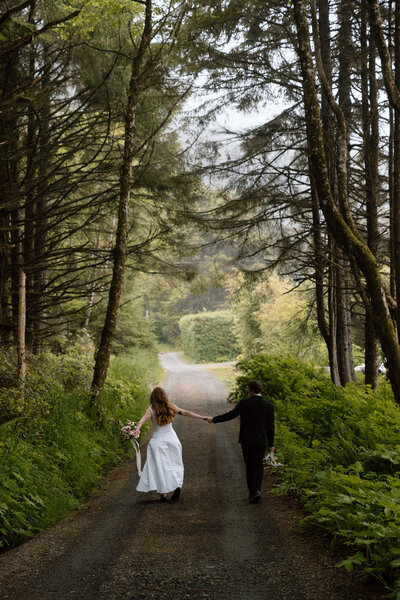 Couple walking down a tree-lined road on the Oregon Coast.
