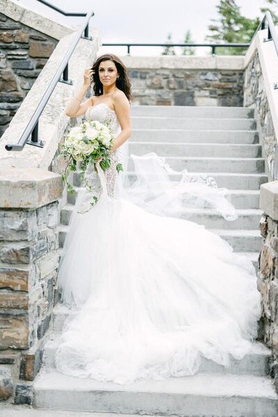 A portrait of a bride standing on steps of the Banff Springs Hotel in Banff National Park