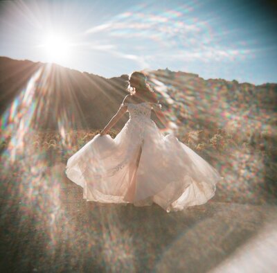 Bride twirling in golden light with sunflare over the mountains, captured by an artistic Washington wedding photographer.