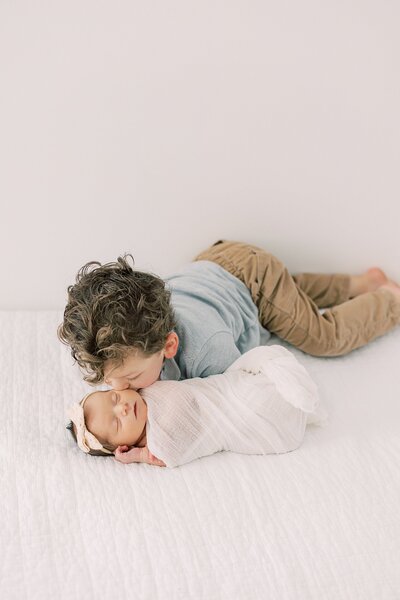 big brother kisses his newborn baby sister during their photography session with West Chester newborn photographer Samantha Jay