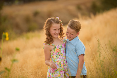 Brother and sister in a sunlit field in Boise.