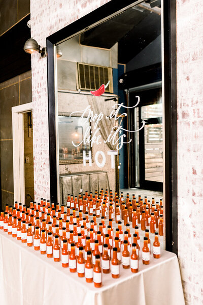 hot sauce bottle escort card display with mirror that says "Drop it Like It's Hot" with a pepper illustration