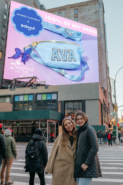 Two teenage girls standing in front of a billboard