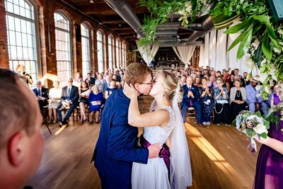 Couple's first kiss during wedding ceremony at The Cotton Room