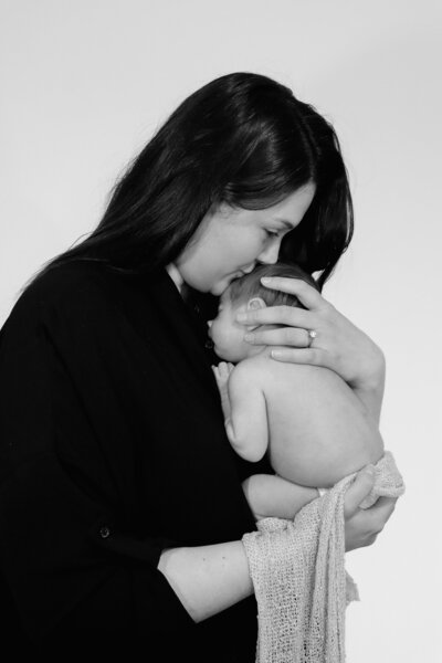 Mother holding newborn baby in natural light home session Buxton High Peak