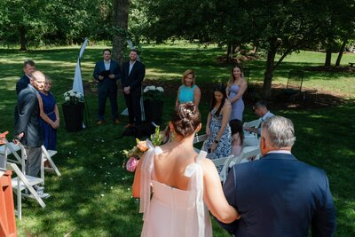 Bride walking down the aisle for her backyard wedding at her fiancē's family home in Fairfax, VA.    