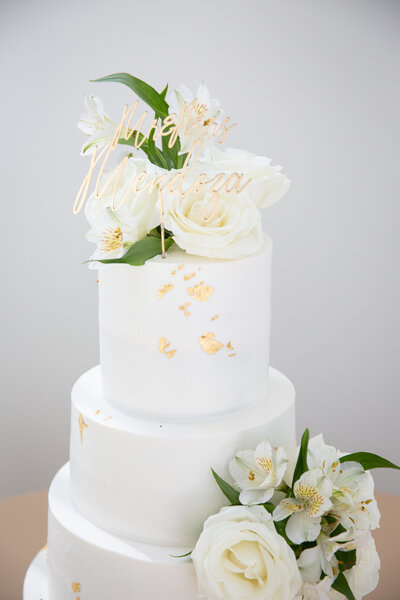 An Austin-based wedding photographer captures a stunning white wedding cake adorned with beautiful flowers on top.