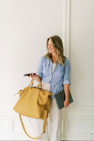 Meghan a film wedding photographer in North Carolina poses with a bag, laptop, and cell phone