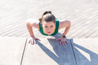 fitness coach doing a push up  wearing a green sleeveless top