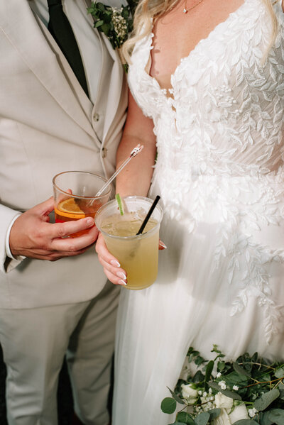 Wedding reception photo at Bear Creek Mountain Resort wedding venue in Macungie, Pa. The groom is picking up the bride and spinning her in celebration of their entrance into their wedding venue while guests cheer around them. The bride and groom are both holding beers and throwing them up in celebration as they share a kiss. Pa wedding reception photos, Pa wedding photos, Pa wedding photographer.