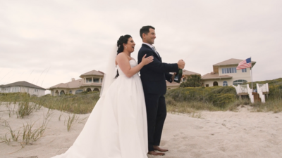 Wedding couple pops champagne bottle on the beach