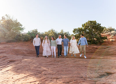 large family walking on red rock in snow canyon and laughing during family photos