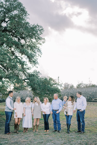 Large family all standing in a row holding hands and smiling at each other