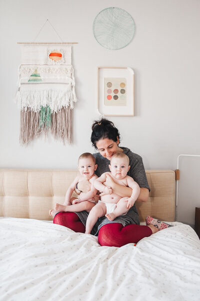 mom and twin baby girls sitting on bed