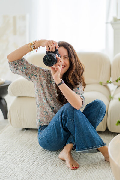 Laure Pascal Glorieux from Laure Photography sitting on the floor taking a picture in front of white backdrop