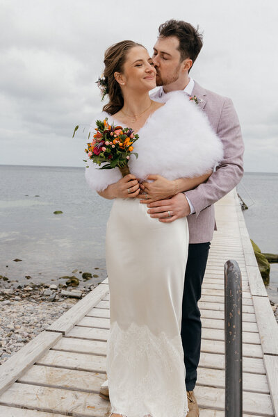 A groom kissing his bride on the Bornholm beach elopement in Europe