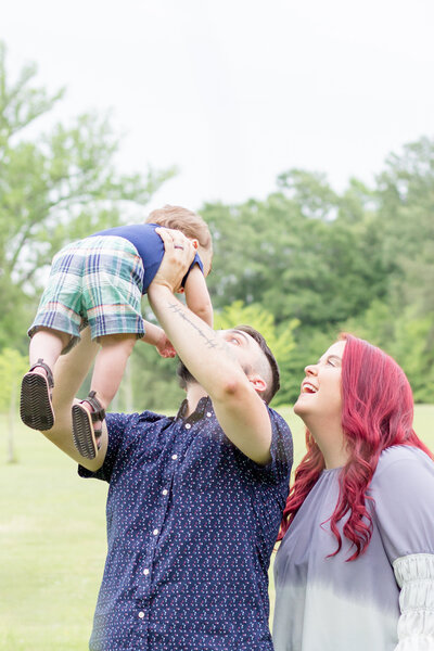 Dad holding up baby with Mom standing beside