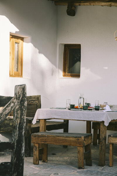 Rustic outdoor dining scene with wooden furniture, beautifully lit by the afternoon sun, captured by Bo Eppink in Ibiza, Spain.