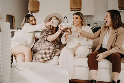 a group of girls cheering their verity of cups as they sit on the couch