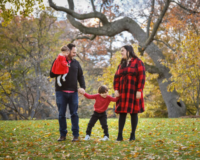 family portrait in the fall outdoor kicking leaves in park