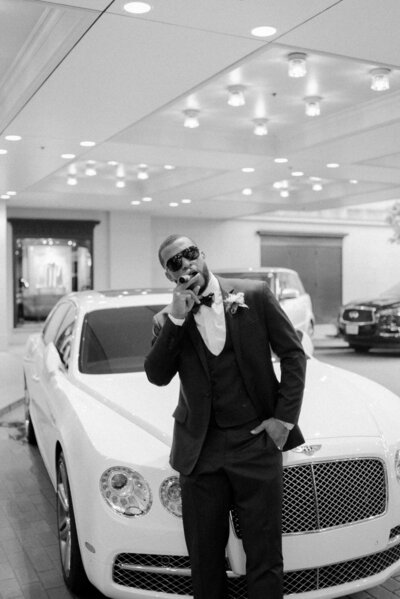 groom smoking a cigar leaning on a bentley