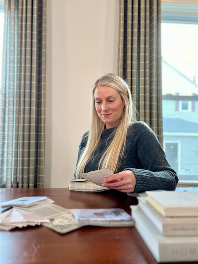 Paint Color Consultant, Just Haley Homes, sitting at her desk  with Benjamin Moore paint swatches for Paint Color Consulting