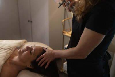 Esthetician performing a facial service in a calming treatment room, part of Maven + Grace’s results-driven skincare offerings

