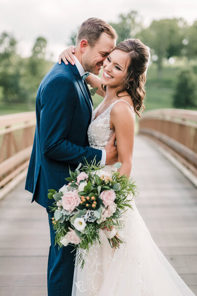 Romantic portrait of bride and groom embracing with bouquet in hand, photographed by Pittsburgh wedding photographer Amber Marie.