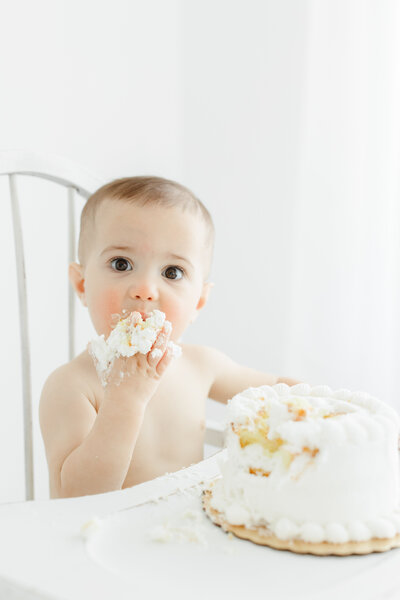 One year old baby boy smashes a cake during portrait session
