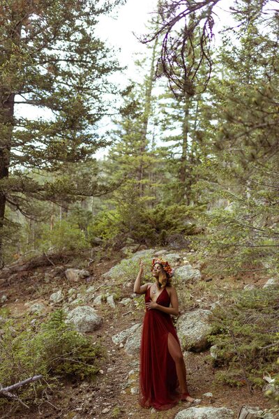 woman with a flower crown and a red dress standing in the forest