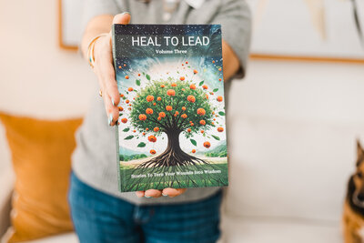 a woman's hands holding out the book Heal to Lead