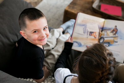 Kid reading while other kid looks at camera | Family Photography Session