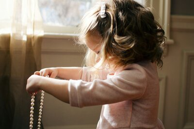 Young girl holding a string of pearls in soft sunlight, symbolizing innocence, hope, and the precious gift of adoption.