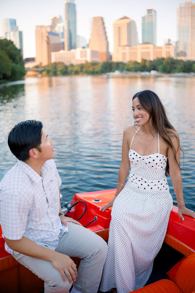 Couple on a retro boat on Lady Bird Lake during their Austin engagement session, with soft golden light and downtown skyline in the background.