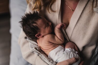Newborn baby in diaper in mom's arms during  Seattle newborn photo session